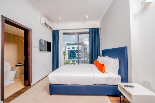 a bedroom with a blue and white bed and a window at Urban by CityBlue Hotel, Dar es Salaam in Dar es Salaam