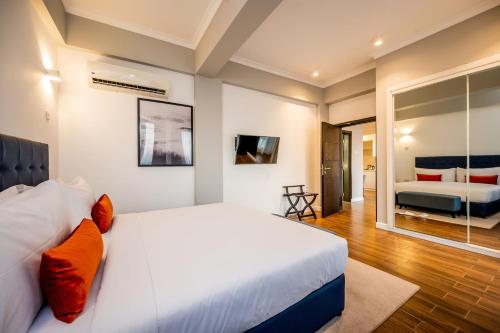 a bedroom with a large white bed with orange pillows at Urban by CityBlue Hotel, Dar es Salaam in Dar es Salaam