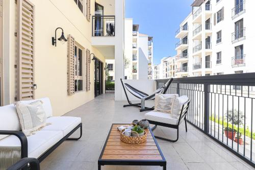 a balcony with two couches and a table and chairs at HiGuests - Luxurious Boho Beach 2BR Apartment in La Mer in Dubai