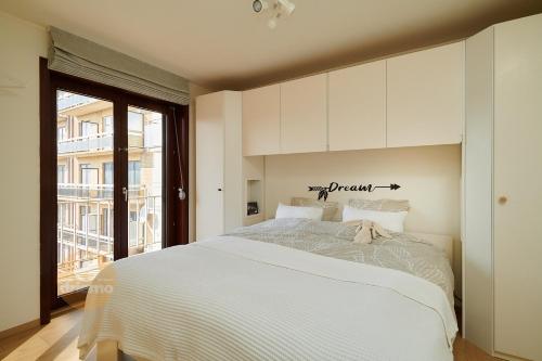 um quarto com uma grande cama branca e uma janela em DUIN 0503 - Appartement voor 8 personen em De Panne