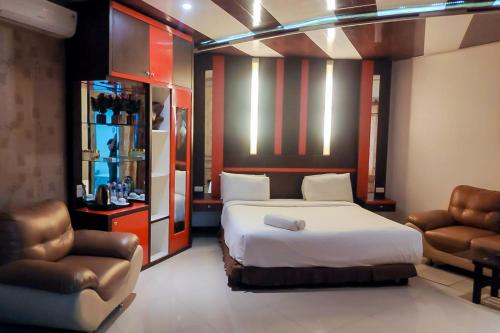 HiliotaluwaにあるSummarend Hotel RedPartnerのベッドと椅子2脚があるホテルの部屋