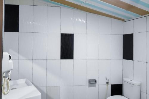y baño con aseo blanco y azulejos blancos y negros. en Summarend Hotel RedPartner en Hiliotaluwa