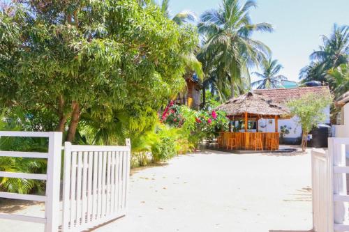 a white fence in front of a house with trees at Lucky Bay in Arugam Bay