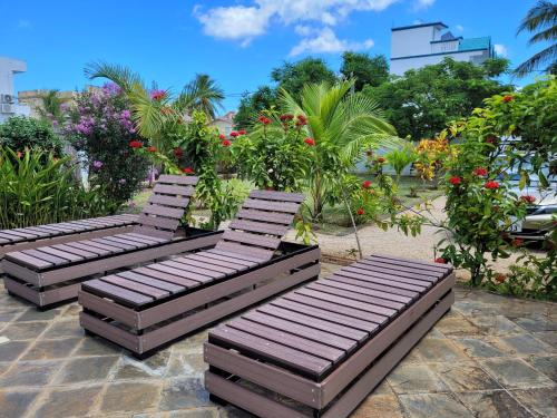 three wooden chairs sitting on a patio with flowers at Villa Kayana in Flic-en-Flac