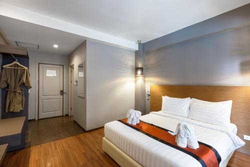 a hotel room with a bed with white towels on it at The Cottage Suvarnabhumi in Lat Krabang