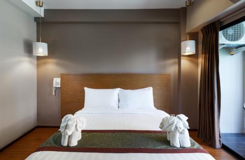 a bedroom with a bed with white pillows and elephantsitures at The Cottage Suvarnabhumi in Lat Krabang