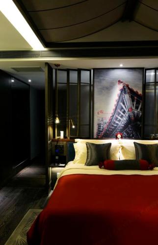 a bedroom with a red bed with a large painting on the wall at Mehood Elegant Hotel Xi'an Big Wild Goose Pagoda Tang Dynasty City in Xi'an