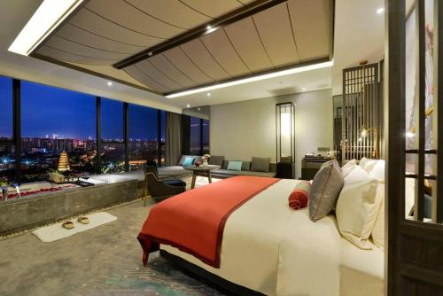 a bedroom with a large bed with a view of a city at 西安大雁塔大唐不夜城美豪雅致酒店 in Xi'an