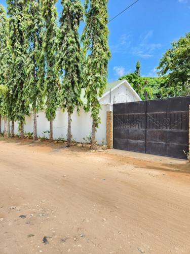 une maison blanche avec une clôture noire et des arbres dans l'établissement Zuri homes (Mtwapa), à Mtwapa