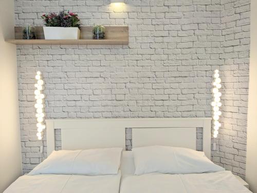 リュブリャナにあるMetelkovaの白レンガの壁と白いベッドが備わるベッドルーム1室