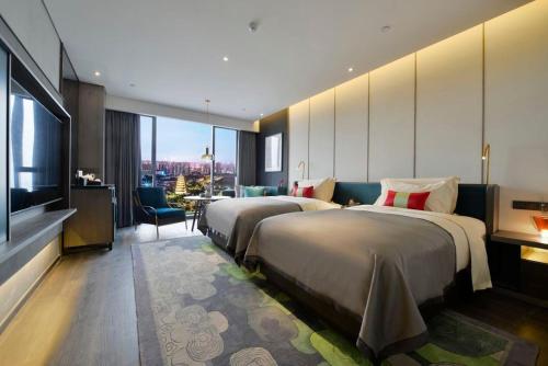a hotel room with two beds and a television at Mehood Elegant Hotel Xi'an Big Wild Goose Pagoda Tang Dynasty City in Xi'an
