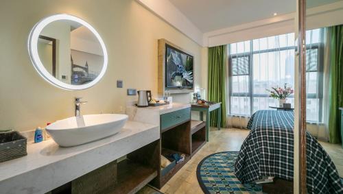 Mehood Theater Hotel, Changzhou Dinosaur Park في تشانغتشو: حمام مع حوض ومرآة كبيرة
