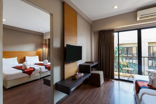 a hotel room with a bed and a tv at The Cottage Suvarnabhumi in Lat Krabang