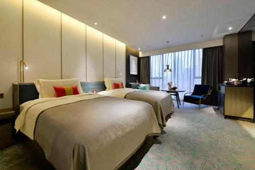 a hotel room with two beds and a desk at Mehood Elegant Hotel Xi'an Big Wild Goose Pagoda Tang Dynasty City in Xi'an