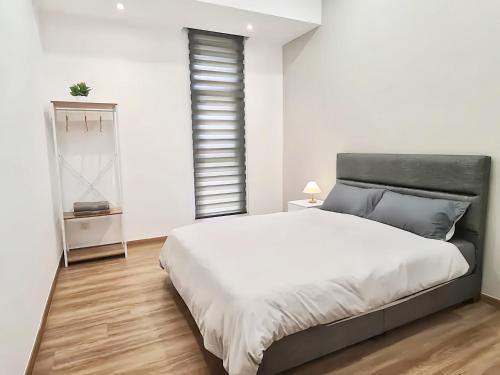 a white bedroom with a large bed and a window at The Cove Hillside Residence Ipoh in Ipoh