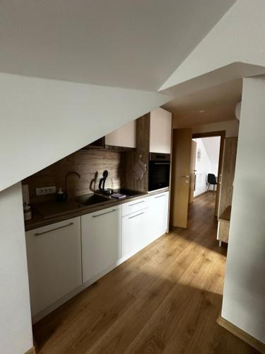 a kitchen with white cabinets and a wooden floor at Apartmani Lotus Vrdnik in Vrdnik