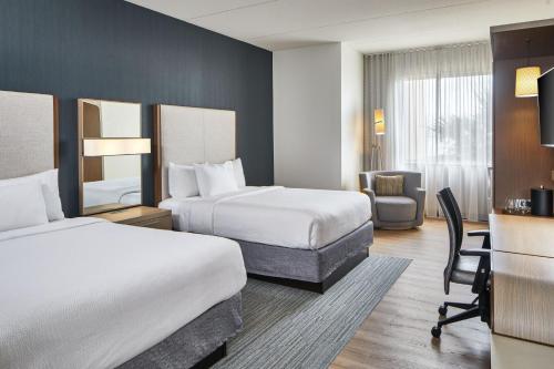 a hotel room with two beds and a desk at Courtyard by Marriott St. Petersburg Clearwater/Madeira Beach in St Pete Beach