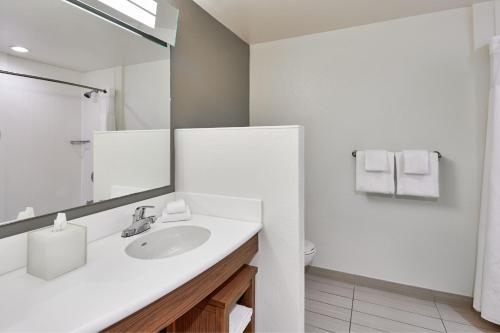 a white bathroom with a sink and a mirror at Courtyard by Marriott St. Petersburg Clearwater/Madeira Beach in St Pete Beach
