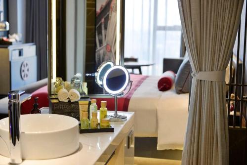 a bathroom with a sink and a bed with a mirror at Mehood Elegant Hotel Xi'an Big Wild Goose Pagoda Tang Dynasty City in Xi'an