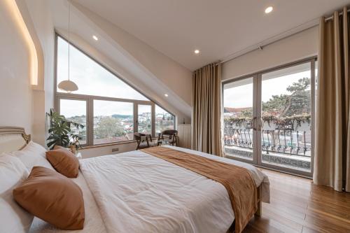 een slaapkamer met een groot bed en grote ramen bij Jodi Dalat Hotel in Da Lat