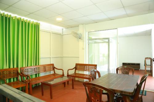 uma sala de jantar com cortinas verdes e mesas e cadeiras de madeira em Green View Lodge em Deniyaya
