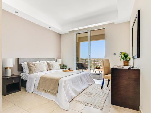 a white bedroom with a large bed and a balcony at Sanders Seaview Paphos in Chlorakas