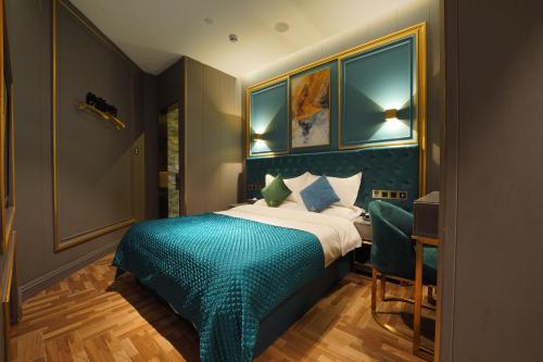 a bedroom with a bed with a blue bedspread and a desk at Mehood Hotel Shanghai Lujiazui in Shanghai