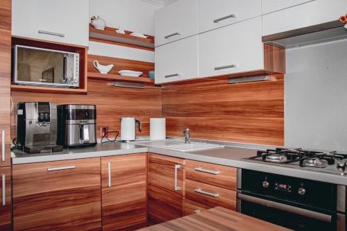 a kitchen with wooden cabinets and a sink and a microwave at Contact Apartman in Bardejov