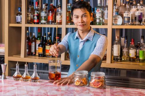a man standing behind a bar with a drink at Courtyard by Marriott Singapore Novena in Singapore