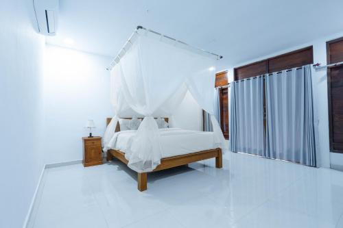 a white bedroom with a bed with a canopy at Arshaka Villa in Amed