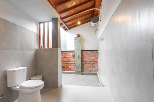 a bathroom with a toilet and a brick wall at Arshaka Villa in Amed
