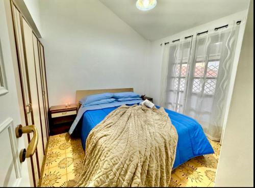 um quarto com uma cama azul e uma janela em Luigia House em Marina di Cerveteri