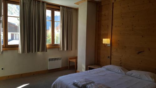 une chambre avec un lit dans une pièce avec des fenêtres dans l'établissement Cortina - 11 - Appart grande terrasse - 8 pers, à Les Deux Alpes