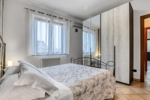 1 dormitorio blanco con 1 cama y 2 ventanas en Il Conero Bilocale con posto auto privato, en Osimo