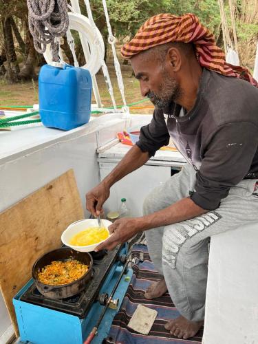 a man cooking food in a pot on a stove at Felucca Sailing Boat Overnight Experience in Aswan