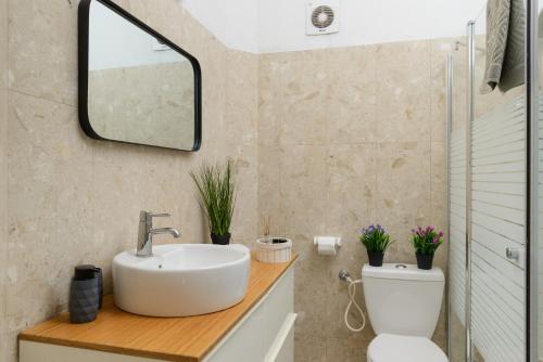 a bathroom with a sink and a toilet and a mirror at Bauhaus 2BR with Sea View & Balcony by FeelHome in Tel Aviv