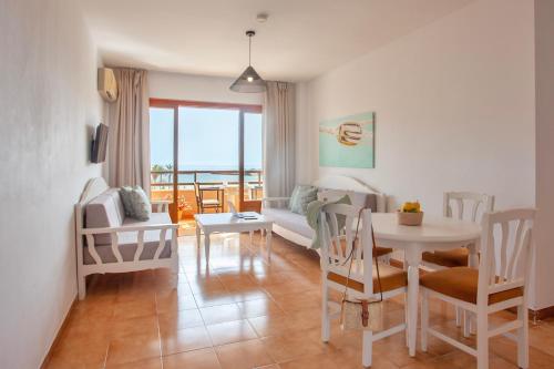 een woonkamer met een bank en een tafel en stoelen bij BJ Playamar Hotel & Apartamentos in S'Illot
