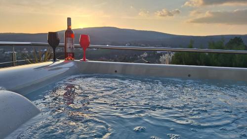 a hot tub with a bottle of wine and a glass at Hillside Cottage in Pécs