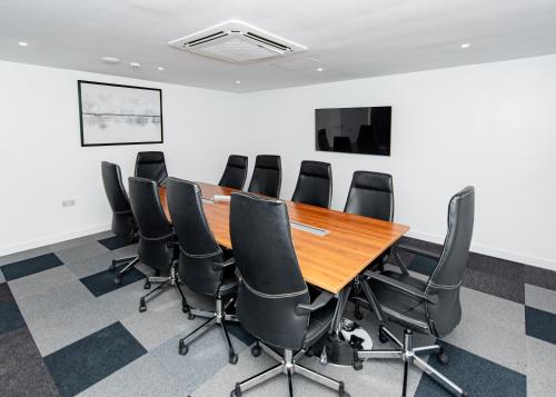 a conference room with a wooden table and black chairs at Urban by CityBlue Hotel, Dar es Salaam in Dar es Salaam
