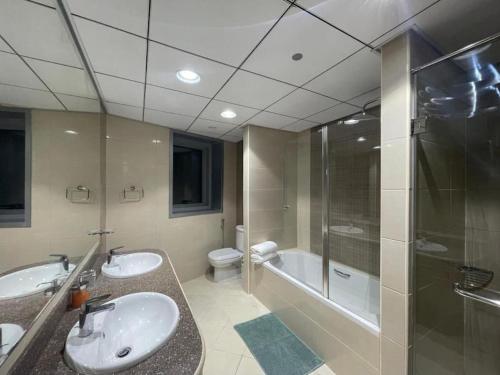 a bathroom with two sinks and a shower and a toilet at Luxury Home Corniche Tower 2 BHK pool gym wifi 20min Dubaï in Ajman 