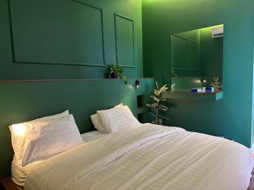 1 dormitorio con cama blanca y pared verde en شاليهــات داكــن, en Butainiyāt