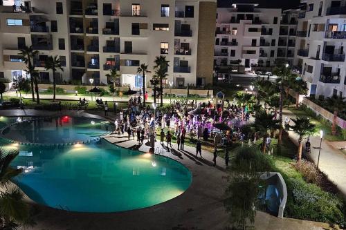 a group of people standing around a swimming pool at night at MARTIL COSTA MAR Appartement de Luxe in Martil
