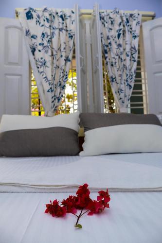 a white bed with red flowers on top of it at Ichhepuron (My Home) in Shānti Niketan