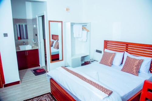 1 Schlafzimmer mit einem großen Bett und einem Badezimmer in der Unterkunft WILLOW INN in Dodoma