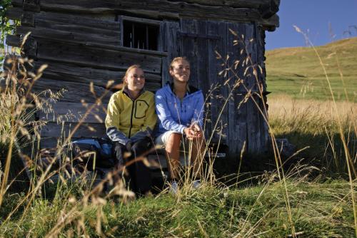 two people sitting in front of an old cabin at Hotel Waldruhe in Gsies