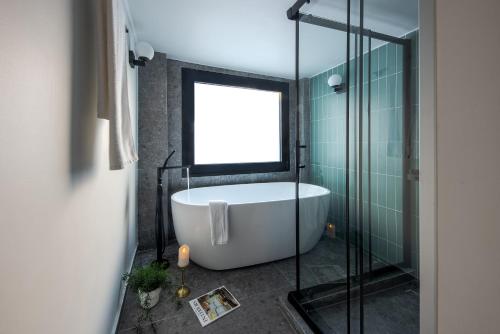 a bathroom with a tub and a glass shower at Bonnie Athens by Nin&Bau in Athens