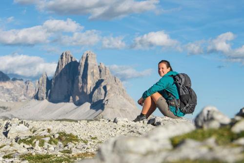 a woman with a backpack sitting on top of a mountain at Hotel Waldruhe in Gsies
