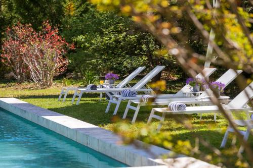 a group of chairs and tables next to a pool at La Bastide de Damien, 5 clefs Demeure d'Exception et Table Remarquable dans le guide Teritoria, JACUZZI Privatif, Cuisine étoilée Dominique Frérard in Aix-en-Provence