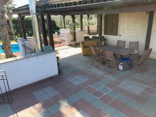 een patio met een tafel en stoelen en een zwembad bij Agriturismo Villa Pina in Lizzanello