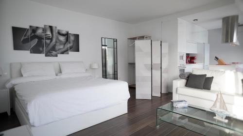 een witte slaapkamer met een wit bed en een bank bij VILLA ANYWAY CONIL Un lujo frente al mar in Conil de la Frontera